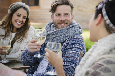 Lächelnde Freunde trinken Wein auf der Terrasse, lizenzfreies Stockfoto