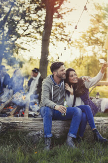 Paar posiert für ein Selfie mit Fotohandy am Lagerfeuer - CAIF10762