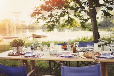 Gartenparty-Mittagessen am Tisch am idyllischen Seeufer - CAIF10764