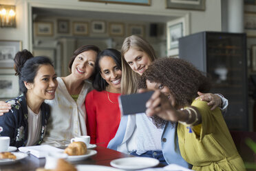 Smiling women friends taking selfie at restaurant table - CAIF10775