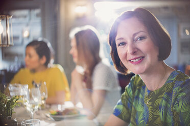 Porträt einer lächelnden Frau, die mit Freunden an einem Restauranttisch speist - CAIF10788