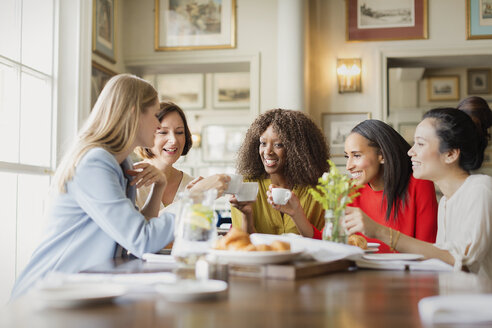 Lächelnde Frauen trinken Kaffee und unterhalten sich am Restauranttisch - CAIF10791