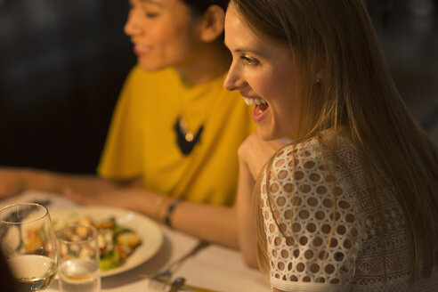 Lächelnde Frau beim Essen mit Freunden am Restauranttisch - CAIF10794