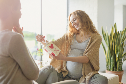 Lächelnde schwangere Frau erhält Geschenk von Freund, lizenzfreies Stockfoto