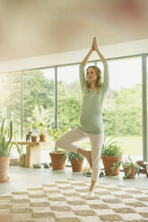 Schwangere Frau beim Üben der Yoga-Baum-Pose - CAIF10817