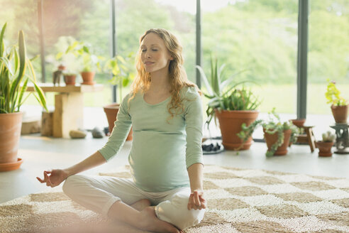 Pregnant woman meditating in lotus position - CAIF10834