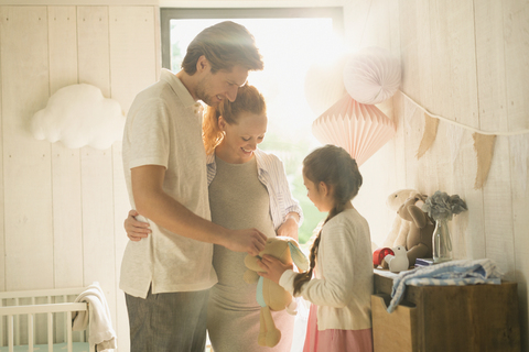 Schwangere Familie mit Plüschtier im Kinderzimmer, lizenzfreies Stockfoto