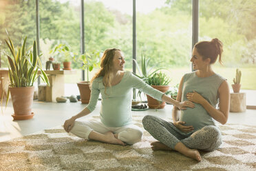 Schwangere Frauen berühren in der Yogastunde den Bauch - CAIF10850
