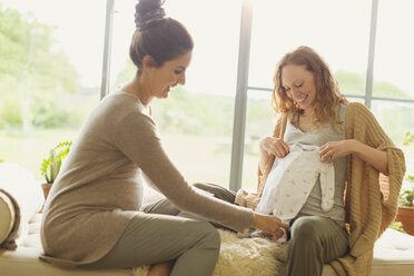 Schwangere Frauen sehen sich Babykleidung an - CAIF10886