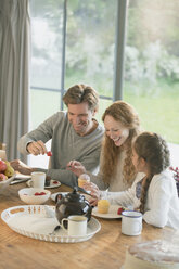 Familie isst Cupcakes und Obst am Esstisch - CAIF10913