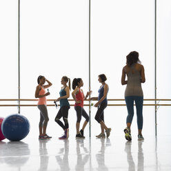 Frauen unterhalten sich und trinken Wasser in einem Fitnessstudio - CAIF10925