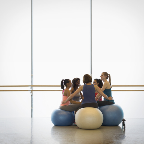 Frauen auf Fitnessbällen im Kreis verbunden in Übung Klasse Fitnessstudio Studio, lizenzfreies Stockfoto