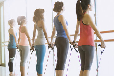Frauen, die mit Widerstandsbändern an der Stange im Fitnessstudio trainieren - CAIF10962