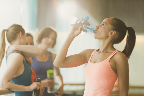 Frau trinkt Wasser im Fitnessstudio, lizenzfreies Stockfoto