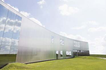Modernes Gebäude mit Reflexion und Rasen unter sonnigen blauen Himmel mit Wolken - CAIF10988