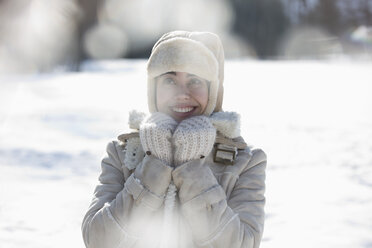 Frau in warmer Kleidung lächelnd im Schnee - CAIF11020