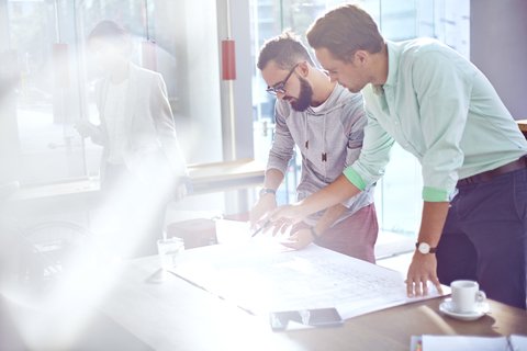 Architekten, die in einem sonnigen Büro Entwürfe prüfen, lizenzfreies Stockfoto