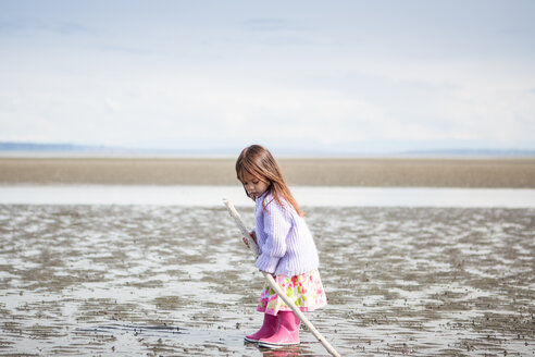 Mädchen mit Stock spielt am Strand - CAIF11058