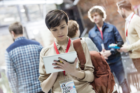 Junge Frau benutzt digitales Tablet auf einer Technologiekonferenz, lizenzfreies Stockfoto