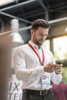 Mann schreibt auf einer Technologiekonferenz eine SMS mit seinem Handy - CAIF11123