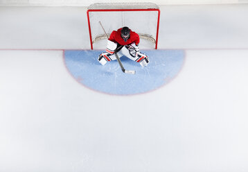 Eishockeytorwart in roter Uniform, der das Tornetz schützt - CAIF11146