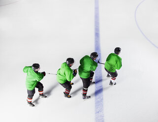 Eishockeyteam in grünen Uniformen, die in einer Reihe auf dem Eis laufen - CAIF11147