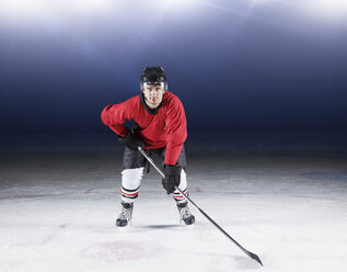 Porträt eines entschlossenen Eishockeyspielers in roter Uniform auf dem Eis - CAIF11148