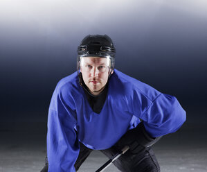 Porträt eines entschlossenen Eishockeyspielers in blauer Uniform auf dem Eis - CAIF11153
