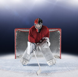 Portrait determined hockey goalie protecting goal net on ice - CAIF11162