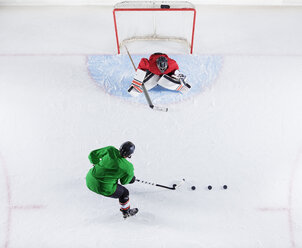 Draufsicht auf einen Hockeyspieler, der mit dem Torwart übt und den Puck auf das Tor schießt - CAIF11163