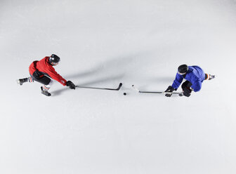 Draufsicht auf Eishockeygegner, die auf dem Eis um den Puck kämpfen - CAIF11166