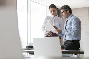 Businessman and businesswoman reviewing paperwork - CAIF11202