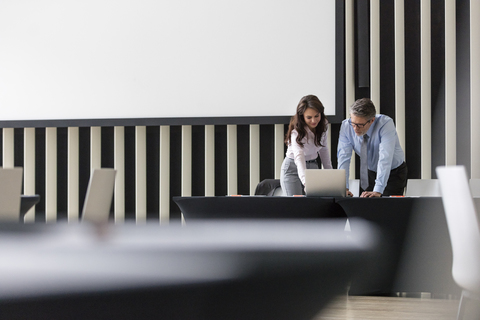 Geschäftsmann und Geschäftsfrau mit Laptop im Konferenzraum, lizenzfreies Stockfoto