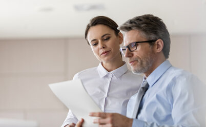 Businessman and businesswoman reviewing paperwork - CAIF11204