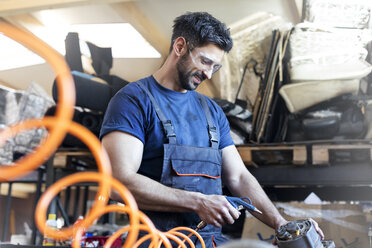 Lächelnder Metallarbeiter bei der Arbeit mit Geräten in einer Werkstatt - CAIF11207