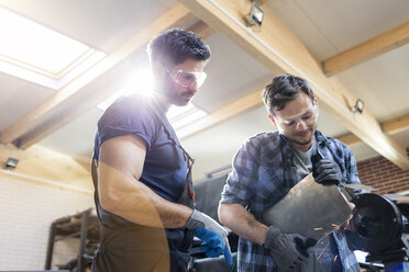 Metal workers using sander in workshop - CAIF11212