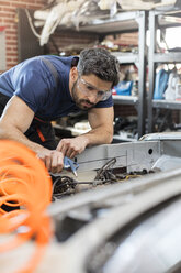 Fokussierter Mechaniker, der ein Auto in einer Autowerkstatt repariert - CAIF11225