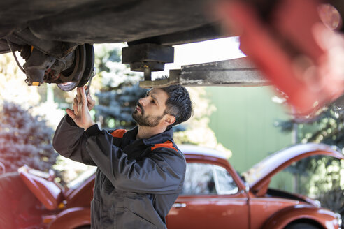 Mechaniker unter dem Auto, der die Bremsen repariert - CAIF11229