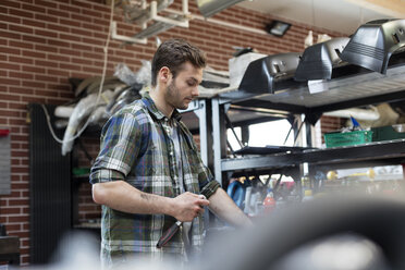 Mechaniker hält Werkzeug in einer Autowerkstatt - CAIF11231