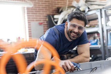 Portrait smiling mechanic working in auto repair shop - CAIF11234