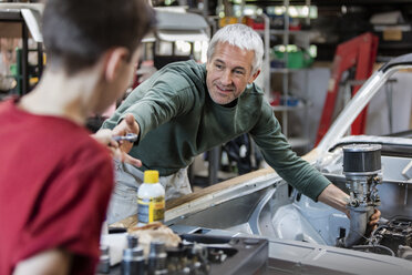 Vater und Sohn bauen den Motor eines Oldtimers in einer Autowerkstatt um - CAIF11236