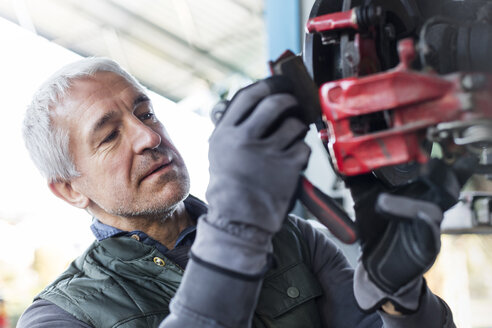 Nahaufnahme fokussiert Mechaniker ersetzt Bremsbeläge in Autowerkstatt - CAIF11239