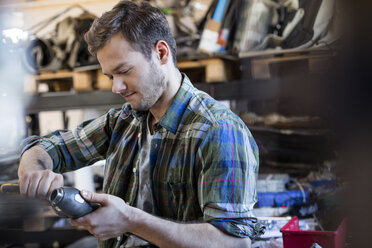Mechanic fixing car part in auto repair shop - CAIF11240