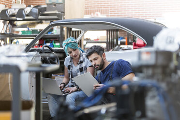 Mechaniker arbeiten mit Klemmbrett und Laptop in einer Autowerkstatt - CAIF11245