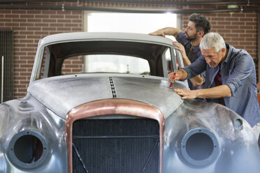 Mechaniker bauen einen Oldtimer in einer Karosseriewerkstatt um - CAIF11265