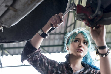 Junge Mechanikerin mit blauen Haaren repariert Auto in Autowerkstatt - CAIF11272