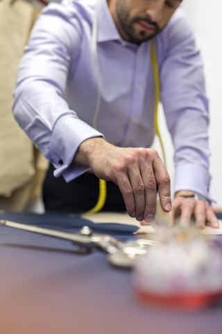 Schneiderin beim Markieren von Stoffen in der Herrenbekleidungswerkstatt, lizenzfreies Stockfoto