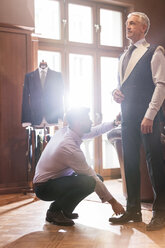 Tailor fitting businessman for suit in menswear shop - CAIF11286