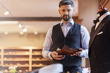 Portrait confident businessman holding dress shoe in menswear shop - CAIF11290