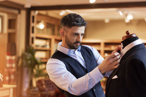 Schneiderin beim Anpassen der Krawatte an einem Schneidermodell in einem Herrenbekleidungsgeschäft - CAIF11291